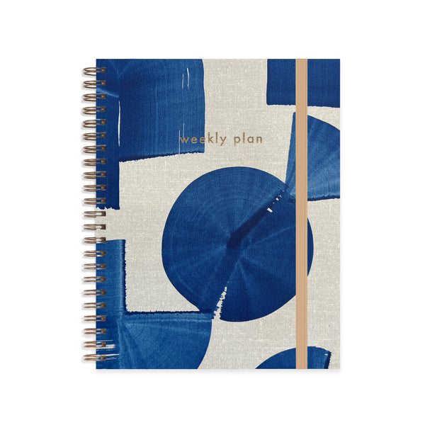 Indigo A5 weekly undated planner notebook by Moglea with a smooth cover and open pages showing weekly layout design.