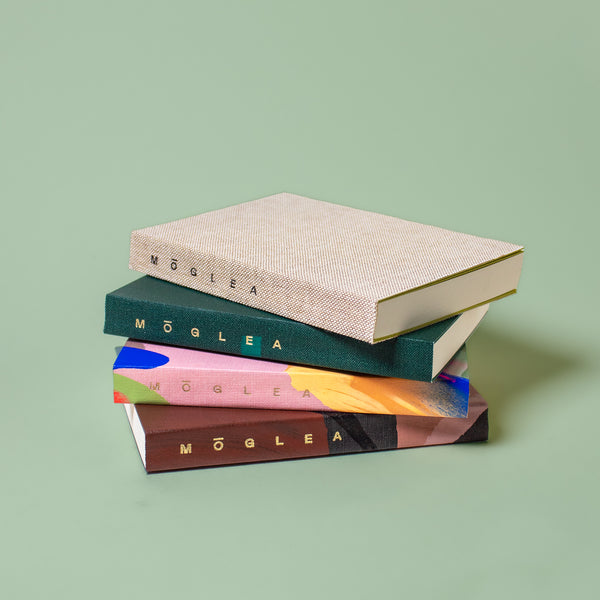 Stack of green Moglea Pocket Softcover Notebooks with rounded corners and a smooth cover for portable note-taking.